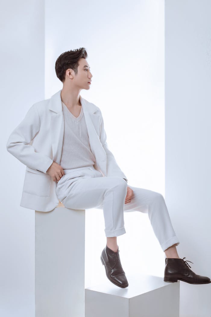 Sophisticated male model posing in a modern, minimalist studio setting wearing stylish white fashion.